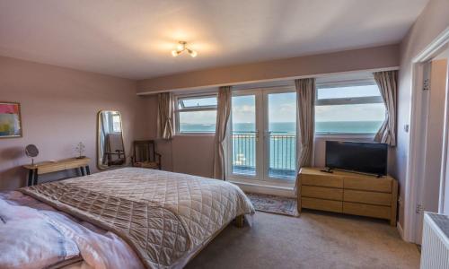 1 dormitorio con cama, TV y balcón en La Mouette en Brixham