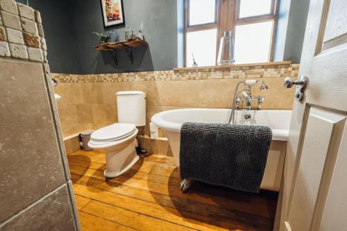 a bathroom with a toilet and a tub and a sink at The Vestry - Sleeps 12 - With Hot Tub in Haworth