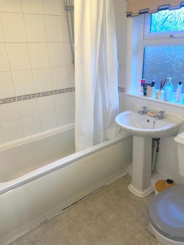 a bathroom with a sink and a tub and a toilet at Relaxing Crewe home in Crewe