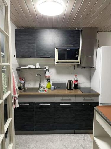 a kitchen with black cabinets and a sink and a microwave at ÖLJERSJÖ COTTAGE in Lyckeby