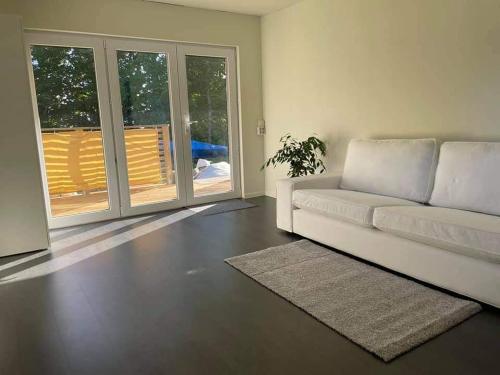 a living room with a white couch and sliding glass doors at ÖLJERSJÖ COTTAGE in Lyckeby