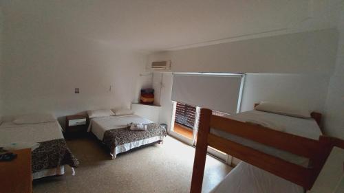 a small room with two beds and a refrigerator at HABITACIONES en casa palermo con terraza y parrilla in Buenos Aires