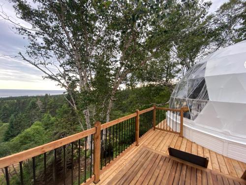 a glass dome on a wooden deck with a view of the ocean at Domes Rocher Percé at Domaine Renard in Perce