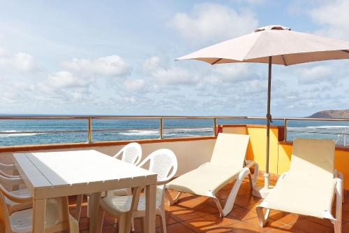 a balcony with a table and chairs and an umbrella at Apartamentos Maype Canteras in Las Palmas de Gran Canaria