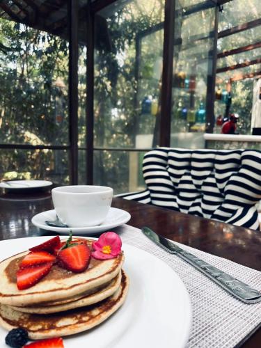 a stack of pancakes with strawberries on a table at Hotel La Casa de los Árboles Immersive Experience in Zacualpan de Amilpas