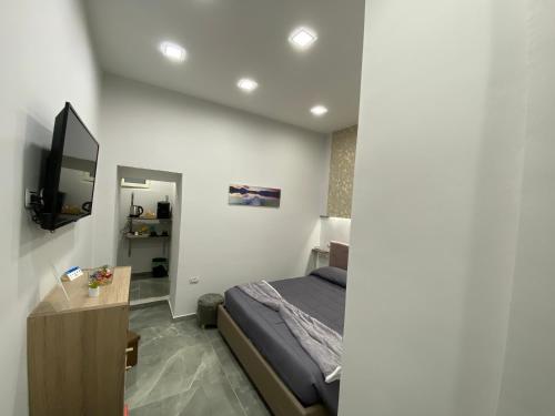 een slaapkamer met een bed en een flatscreen-tv bij Maison Quartieri Spagnoli in Napels