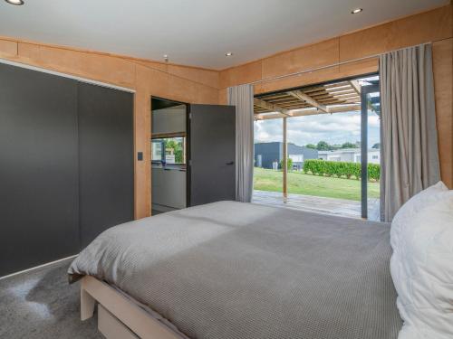 um quarto com uma cama grande e uma janela grande em The Little Bach at Whangapoua em Whangapoua