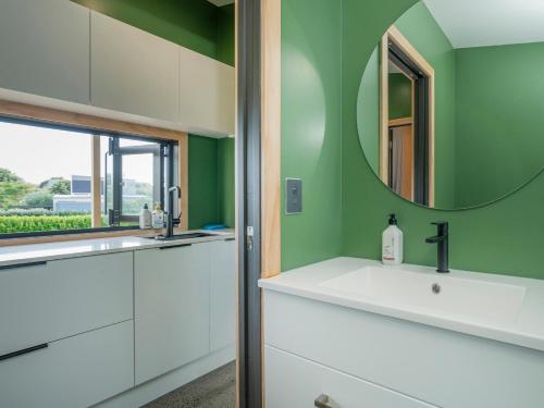 a bathroom with a sink and a mirror at The Little Bach at Whangapoua in Whangapoua