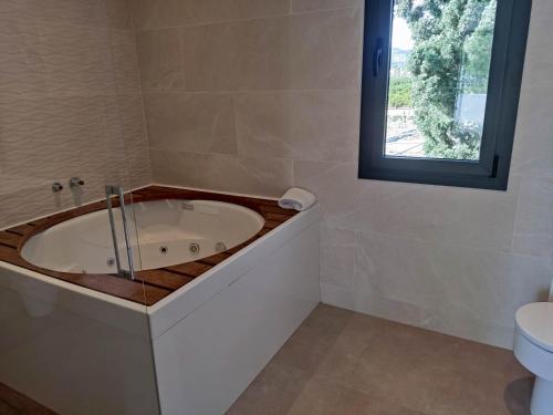 baño con bañera, aseo y ventana en CASA MARISA, en Alcanar