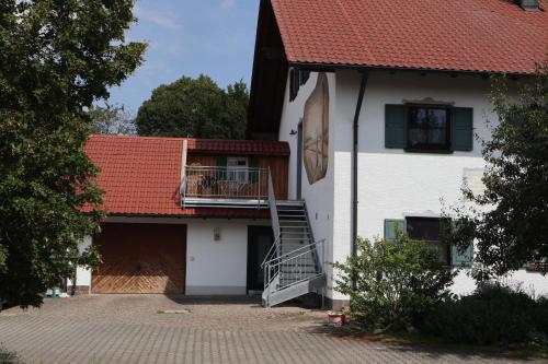 a white house with a red roof and a staircase at Bio-Bauernhof Eisele in Scheuring