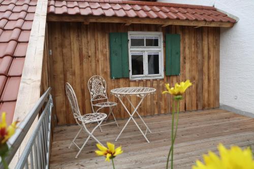 a patio with two chairs and a table on a deck at Bio-Bauernhof Eisele in Scheuring