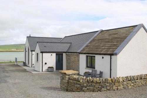 a house with a stone fence in front of it at Congesquoy Barn in Stromness