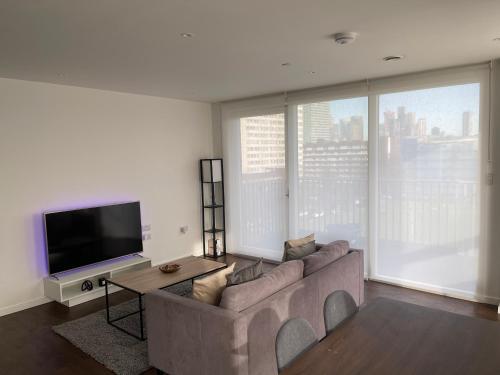 a living room with a couch and a flat screen tv at Immaculate 2bed apartment in London- city views in London