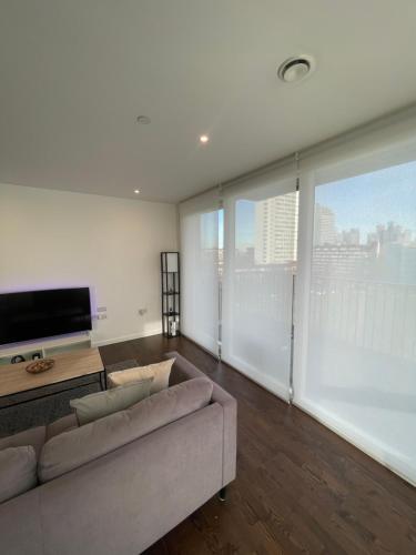 ein Wohnzimmer mit einem Sofa und einem Flachbild-TV in der Unterkunft Immaculate 2bed apartment in London- city views in London