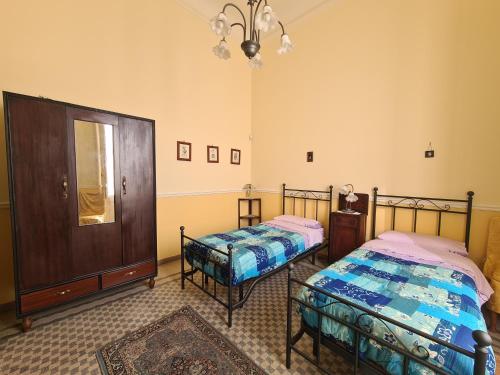 a bedroom with two beds and a mirror and a chandelier at Residenza Maria Letizia in Milo