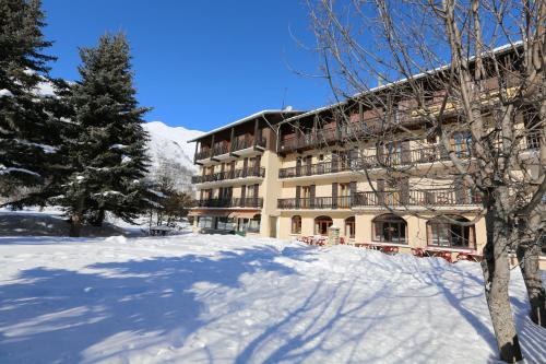a large building in the snow with a snow covered yard at Le Relais du Galibier in Valloire