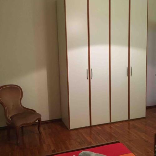 a room with a chair and white cabinets at LA CASA DI AURORA in Ivrea