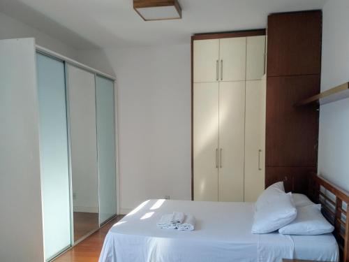 um quarto com uma cama com lençóis brancos e um espelho em Luna Rossa Guest House no Rio de Janeiro