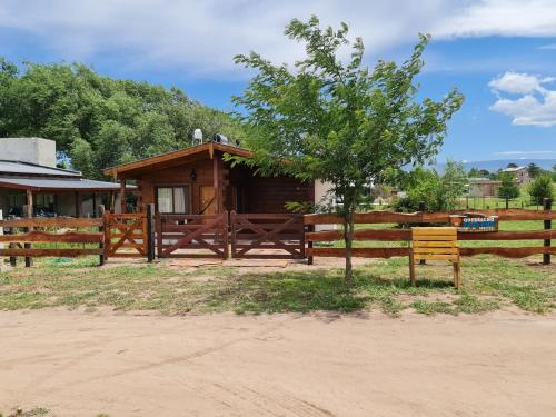 a wooden cabin with a fence and a tree at CABAÑA PRIVADA NALÚ in Villa Ciudad Parque