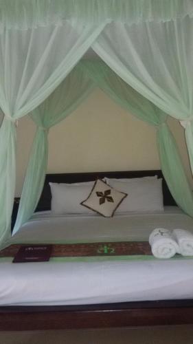 a bed with curtains over it with towels on it at Mans Cottages & Spa in Pemuteran