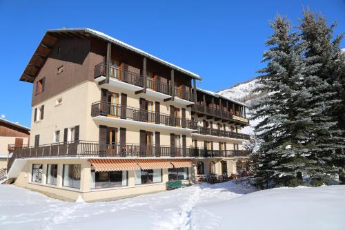 a large building in the snow with a tree at Le Relais du Galibier in Valloire