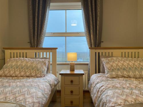 Cottage 427 - Clifden في كليفدين: غرفة نوم بسريرين ونافذة