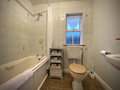 ein Badezimmer mit einer Badewanne, einem WC und einem Waschbecken in der Unterkunft Cottage 427 - Clifden in Clifden