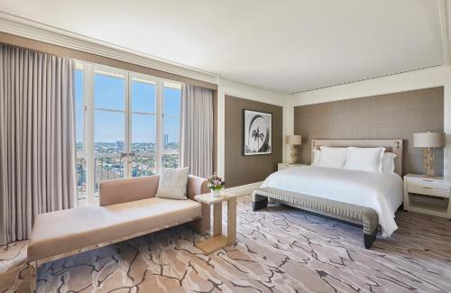 a hotel room with a bed and a couch and windows at Beverly Wilshire, A Four Seasons Hotel in Los Angeles