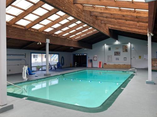 a large swimming pool in a building with a wooden ceiling at Coast Riders Inn in San Simeon