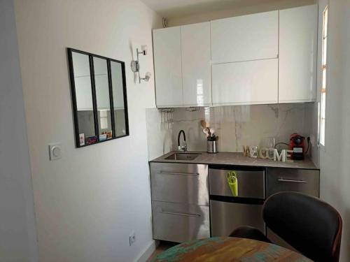 - une cuisine avec des placards blancs, un évier et une table dans l'établissement Bel appartement avec vue imprenable, à Canet