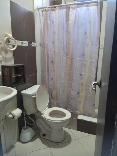 a bathroom with a toilet and a shower curtain at Hostal Casa Taisha in Montañita