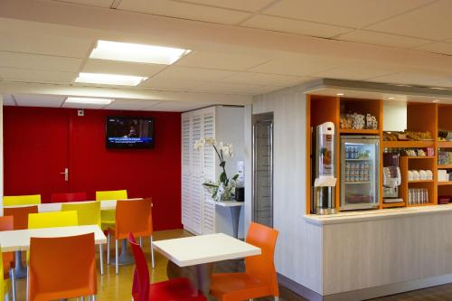 a restaurant with tables and chairs and a refrigerator at Hôtel Olivet Orléans Sud Zénith ex PC in Olivet