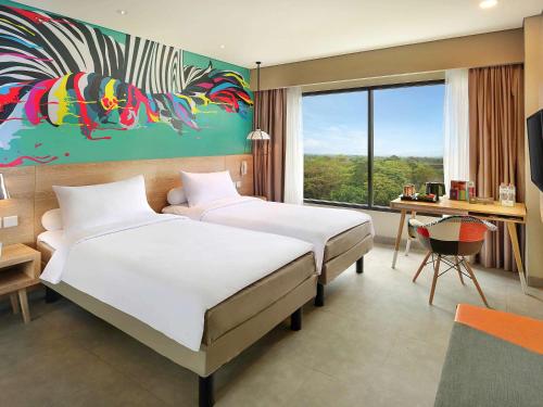 um quarto de hotel com duas camas e uma secretária e uma janela em Ibis Styles Bogor Raya em Bogor