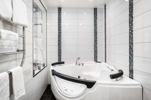 a bath tub in a bathroom with white tiles at Best Western Karlshamn Spa & Relax in Karlshamn
