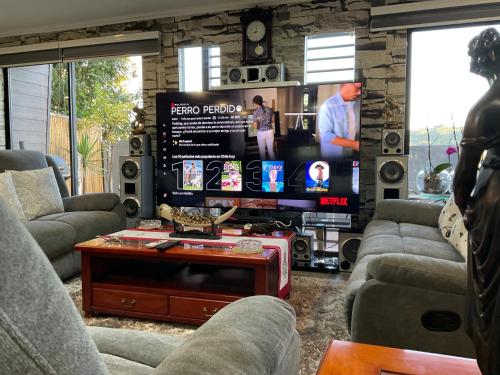 a living room with couches and a tv and a table at Hostal Umantun in Dalcahue