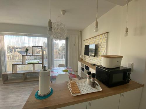 - une cuisine avec un comptoir, un four micro-ondes et une table dans l'établissement Studio Amicie 27m2, balcon couvert, près centre-gare-cathédrale, wifi, à Reims