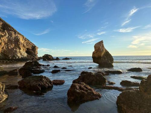 a beach with rocks in the ocean with a blue sky at Coastal Tiny House 2 Queen Beds low loft in San Luis Obispo