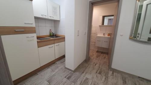 a kitchen with white cabinets and a wooden floor at Neuburg New Apartement in Neuburg an der Donau