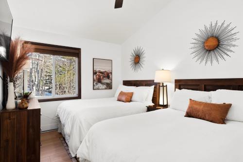 - 2 lits dans une chambre dotée de murs blancs et d'une fenêtre dans l'établissement Terracehouse by Snowmass Vacations, à Snowmass Village