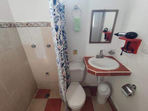 uma casa de banho com um WC, um lavatório e um espelho. em Squalo's Place em Holbox