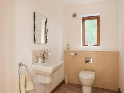 baño con lavabo y aseo y ventana en Isfryn, en Pentraeth