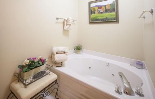 a bathroom with a bath tub with a vase of flowers at Colonial Crest 107 - Great location! - You can walk to town! condo in Pigeon Forge