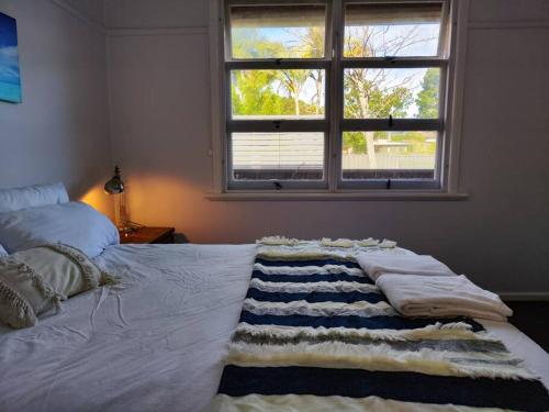a bed with a blanket on it with a window at Seaside Cottage with Jetty in Point Clare