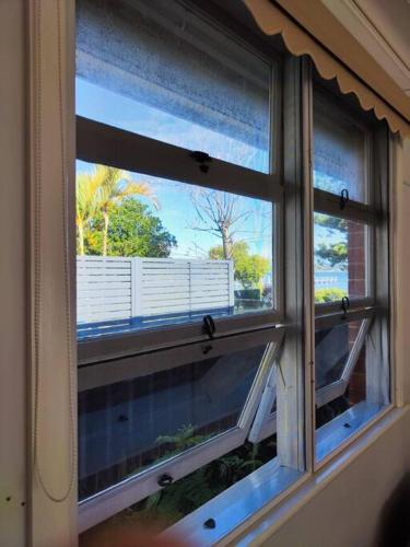 an open window with a view of a balcony at Seaside Cottage with Jetty in Point Clare