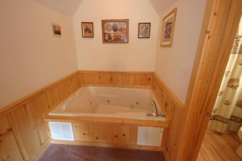 uma grande banheira num quarto com paredes de madeira em ER202 - Now and Forever Great location! - Close to town! cabin em Pigeon Forge