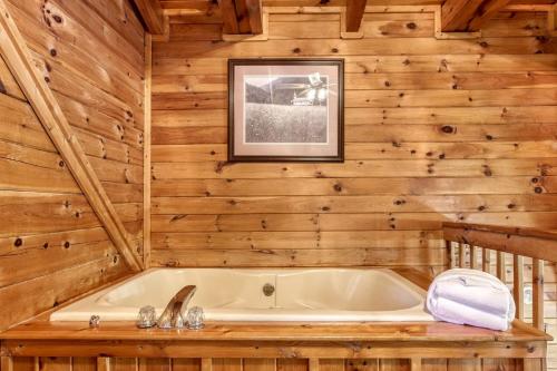 ein Badezimmer mit einer Badewanne an einer Holzwand in der Unterkunft ER5 - Log Heaven - Great location! Close to all the action! cabin in Pigeon Forge