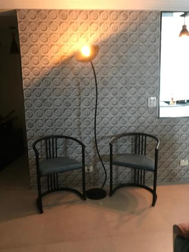 two chairs and a lamp in a living room at Casa com Piscina Canto do Forte - Praia Grande in Praia Grande