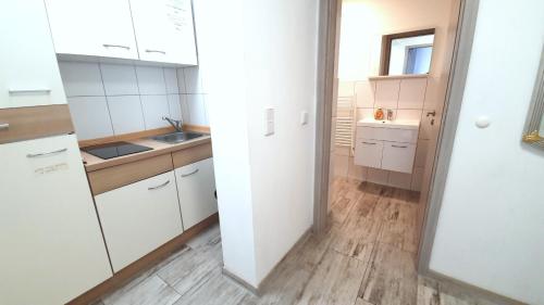a kitchen with white cabinets and a wooden floor at Neuburg Apartment am Schloss in Neuburg an der Donau