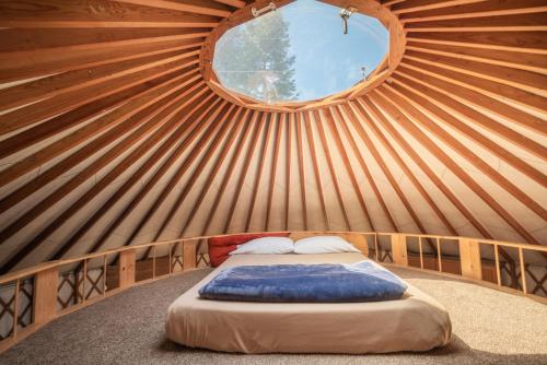 a bed in a yurt with a round window at Strawhouse Resorts in Big Bar