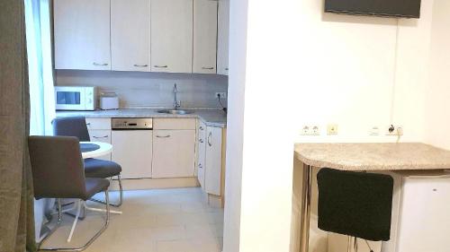 a kitchen with white cabinets and a table and chairs at Neuburg Apartment am Schloss in Neuburg an der Donau